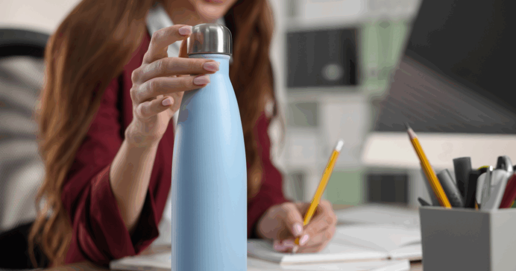 woman working with water bottle on desk